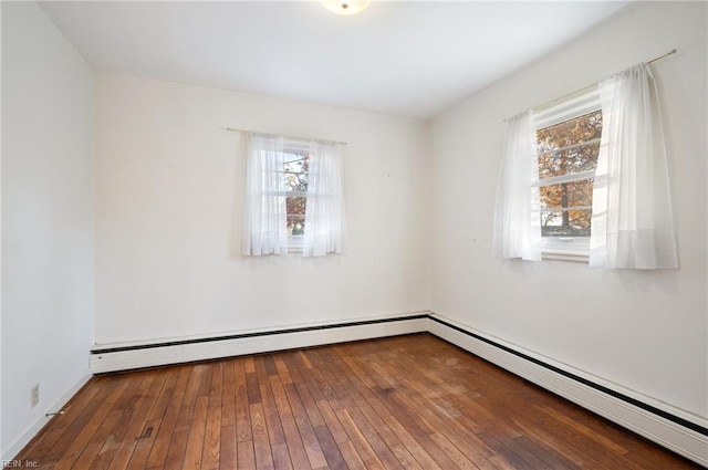 unfurnished room featuring plenty of natural light, a baseboard heating unit, and hardwood / wood-style floors