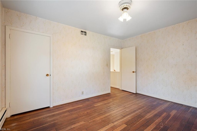 unfurnished room with dark hardwood / wood-style floors and baseboard heating