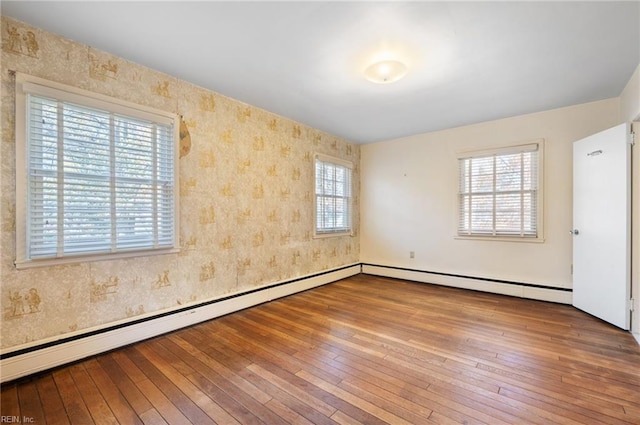 unfurnished room featuring a baseboard heating unit and hardwood / wood-style flooring