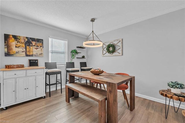 dining room featuring ornamental molding, a textured ceiling, and light hardwood / wood-style floors