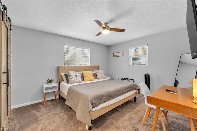 carpeted bedroom featuring ceiling fan, a barn door, and a textured ceiling