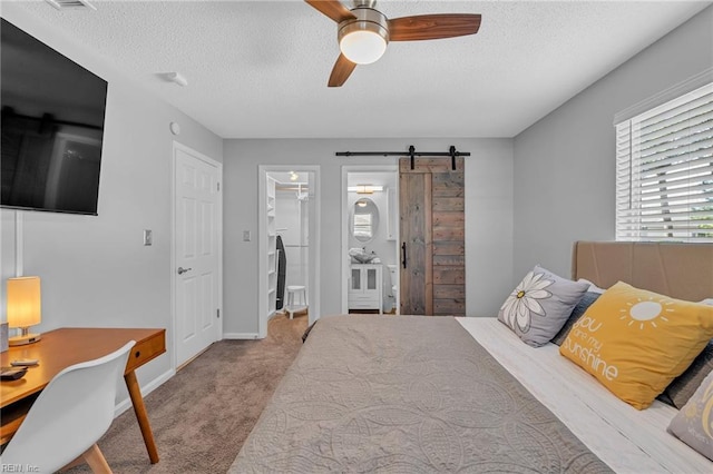 carpeted bedroom featuring ceiling fan, a barn door, a spacious closet, and a textured ceiling