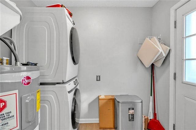 clothes washing area with hardwood / wood-style floors, electric water heater, and stacked washing maching and dryer