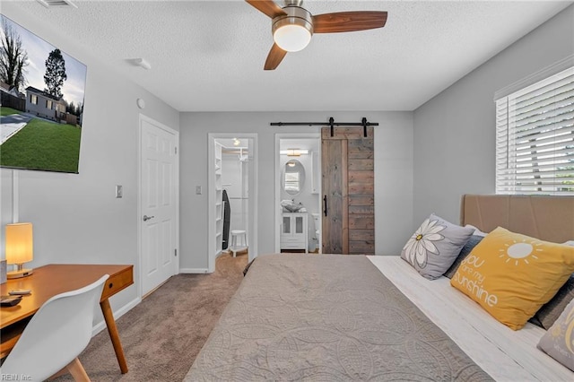 carpeted bedroom featuring ceiling fan, a spacious closet, a barn door, and a textured ceiling