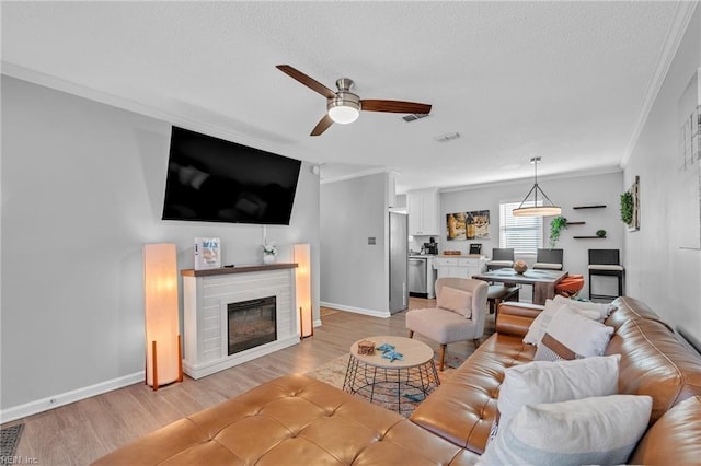 living room with ornamental molding, ceiling fan, and light wood-type flooring