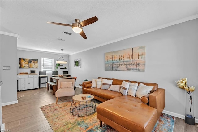 living room featuring wood-type flooring, ornamental molding, and ceiling fan