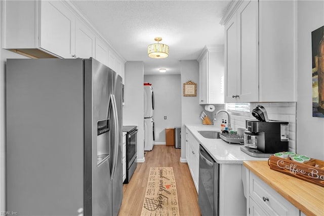 kitchen featuring sink, tasteful backsplash, stainless steel appliances, light hardwood / wood-style floors, and white cabinets