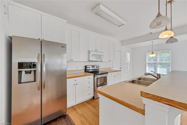 kitchen with decorative light fixtures, white cabinetry, sink, stainless steel appliances, and light hardwood / wood-style flooring