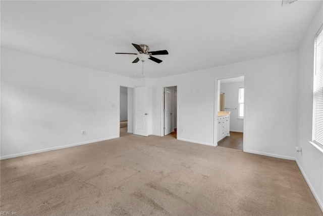 unfurnished bedroom featuring ensuite bathroom, light colored carpet, and ceiling fan