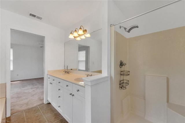 bathroom featuring tile patterned flooring, vanity, and a shower