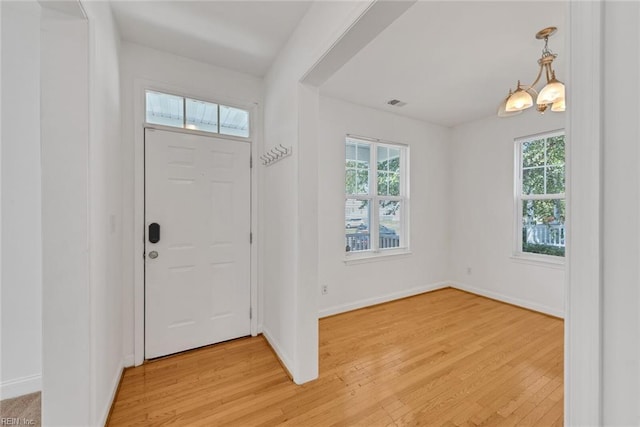 entrance foyer featuring plenty of natural light, a notable chandelier, and light hardwood / wood-style flooring