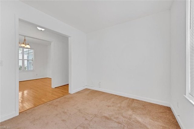 carpeted spare room with a notable chandelier