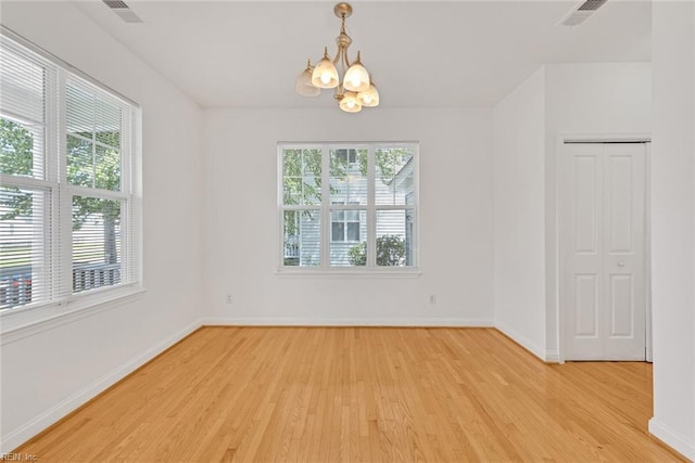 spare room with light hardwood / wood-style flooring and a notable chandelier