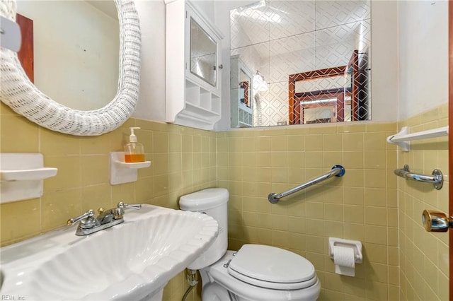 bathroom with sink, tile walls, and toilet