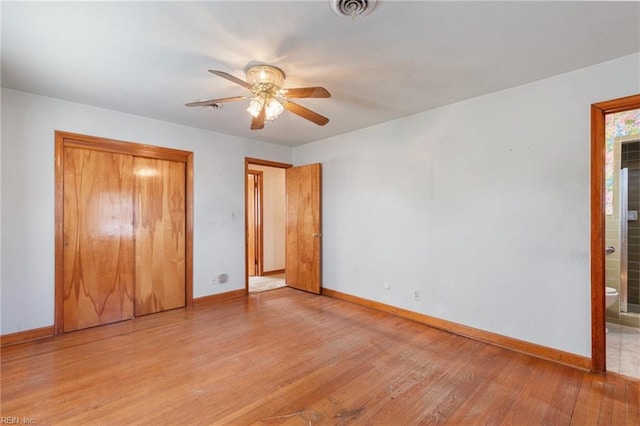 unfurnished bedroom featuring ceiling fan, ensuite bath, light wood-type flooring, and a closet