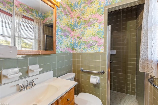 bathroom featuring vanity, toilet, tile walls, and a tile shower