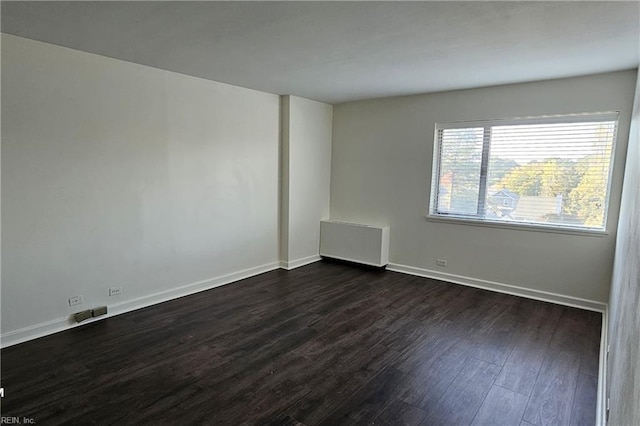 unfurnished room featuring radiator and dark hardwood / wood-style floors