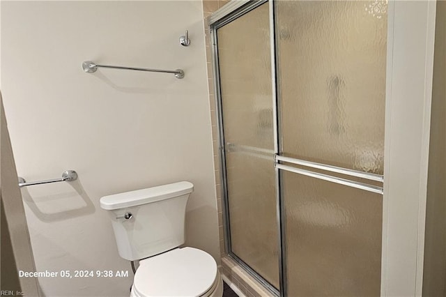 bathroom with a shower with shower door and toilet