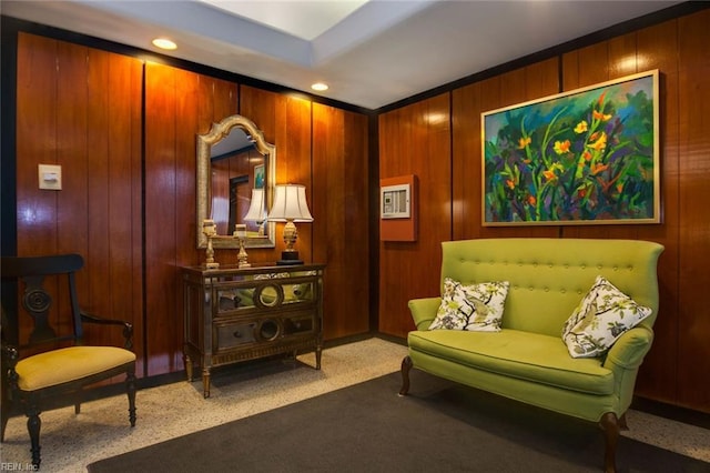 sitting room featuring wooden walls and carpet floors