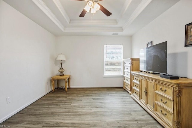 interior space with a tray ceiling, ornamental molding, ceiling fan, and light wood-type flooring