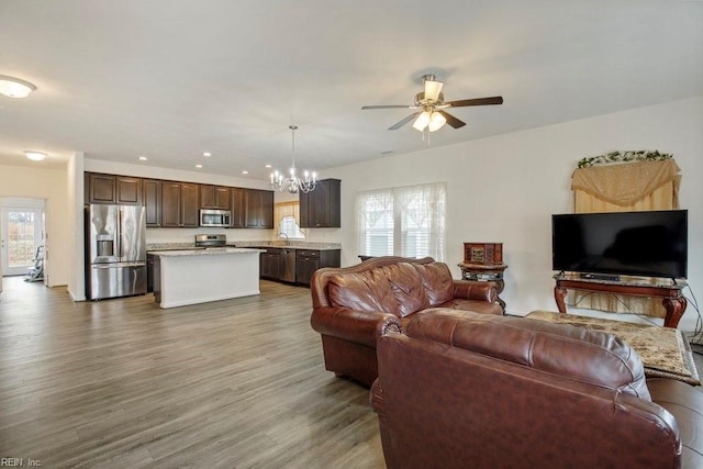 living room featuring ceiling fan with notable chandelier, a healthy amount of sunlight, hardwood / wood-style floors, and sink