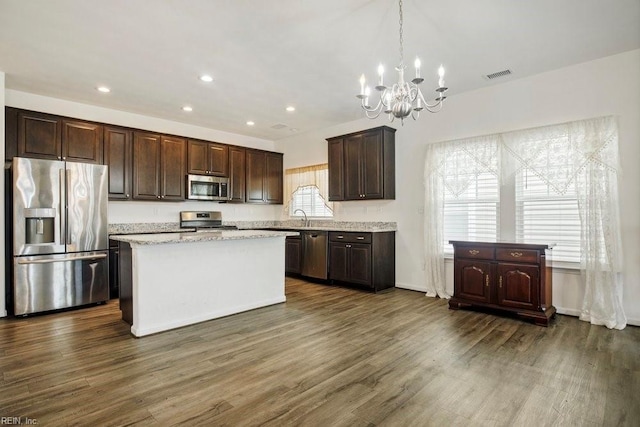 kitchen featuring dark wood-type flooring, stainless steel appliances, a kitchen island, and hanging light fixtures