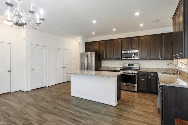 kitchen featuring sink, appliances with stainless steel finishes, hanging light fixtures, a center island, and dark hardwood / wood-style floors