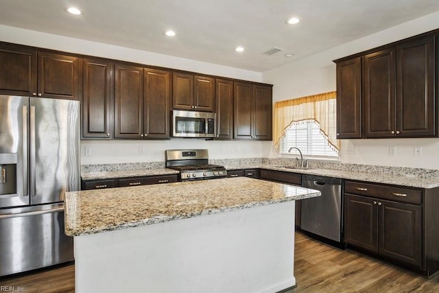 kitchen with a kitchen island, appliances with stainless steel finishes, sink, and dark wood-type flooring