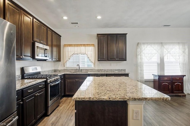 kitchen with sink, light wood-type flooring, stainless steel appliances, and a kitchen island