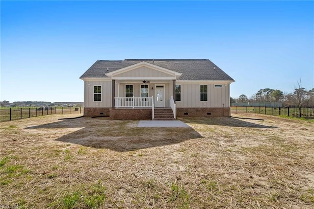 view of front of home with covered porch, a front yard, and a rural view