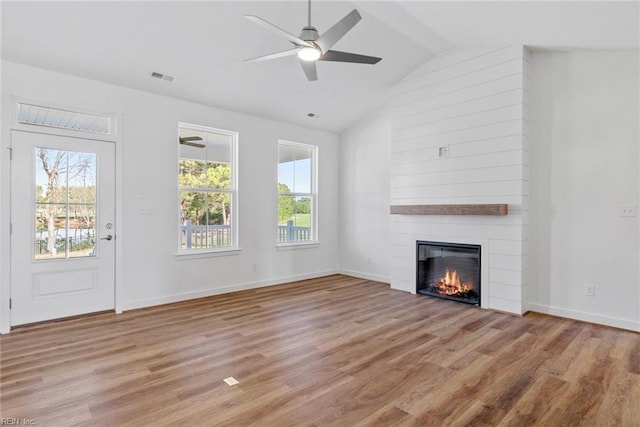 unfurnished living room with vaulted ceiling, ceiling fan, a fireplace, and light hardwood / wood-style flooring