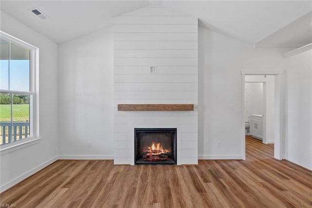 unfurnished living room featuring light hardwood / wood-style flooring, a fireplace, and vaulted ceiling