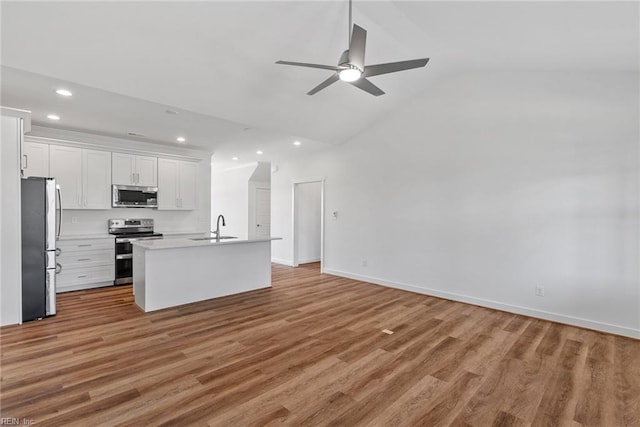 kitchen featuring sink, wood-type flooring, appliances with stainless steel finishes, an island with sink, and white cabinets