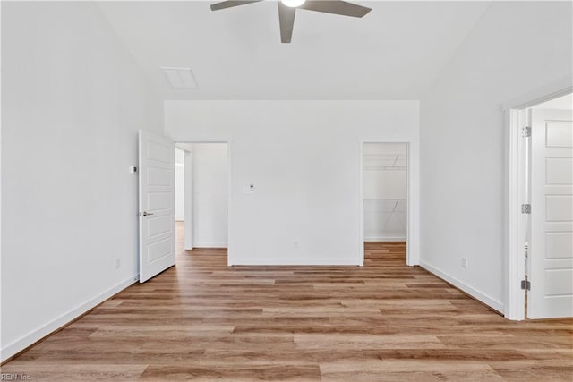 interior space featuring ceiling fan, a walk in closet, lofted ceiling, and light hardwood / wood-style flooring