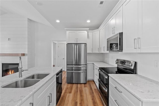 kitchen with light stone counters, sink, white cabinets, and appliances with stainless steel finishes