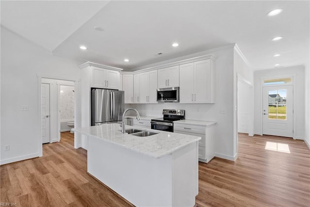 kitchen featuring sink, white cabinetry, stainless steel appliances, light hardwood / wood-style floors, and an island with sink