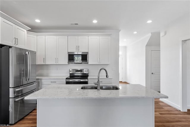 kitchen with sink, an island with sink, stainless steel appliances, light stone countertops, and white cabinets