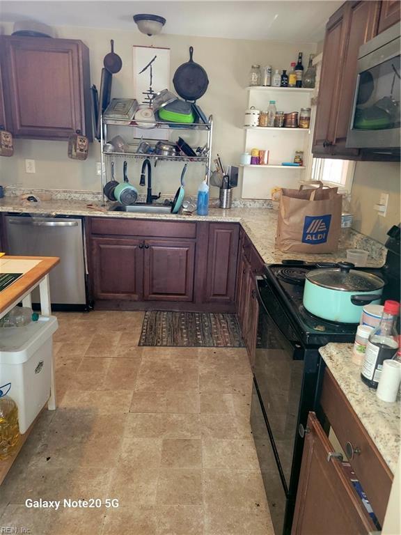 kitchen with light stone counters, sink, and appliances with stainless steel finishes