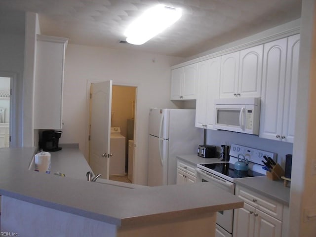 kitchen featuring washer and dryer, sink, white cabinets, kitchen peninsula, and white appliances