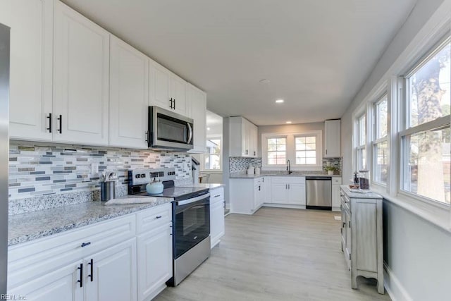 kitchen with backsplash, white cabinets, and appliances with stainless steel finishes