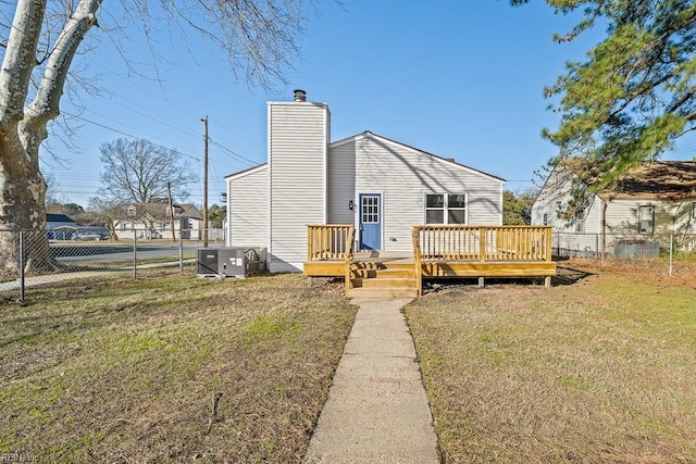 rear view of property featuring central AC unit, a yard, and a deck