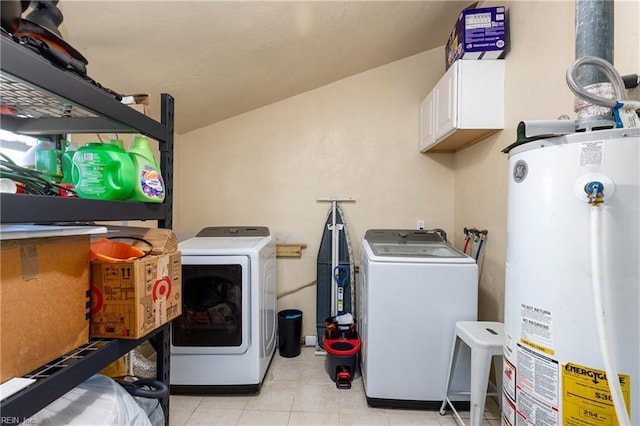 clothes washing area with water heater, washer and dryer, light tile patterned floors, and cabinets