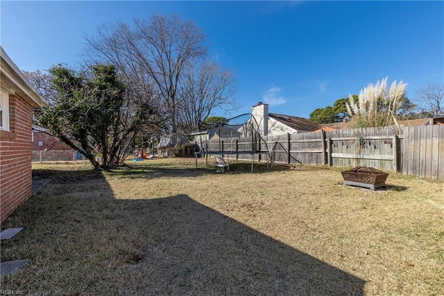 view of yard featuring a trampoline and a fire pit