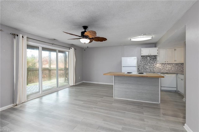 kitchen featuring white appliances, a center island, white cabinets, decorative backsplash, and light wood-type flooring