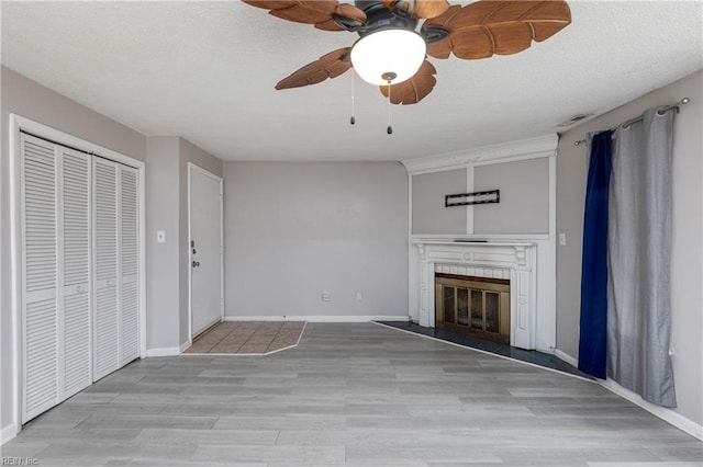 unfurnished living room featuring ceiling fan, light hardwood / wood-style floors, and a textured ceiling