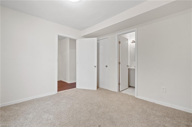 unfurnished bedroom featuring a closet, ensuite bathroom, and light carpet