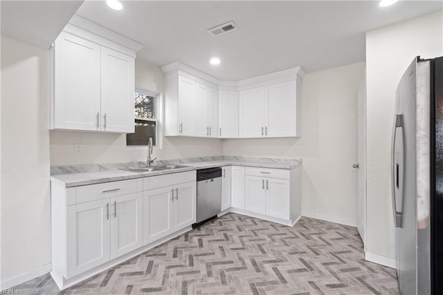 kitchen with appliances with stainless steel finishes, light stone countertops, sink, and white cabinets