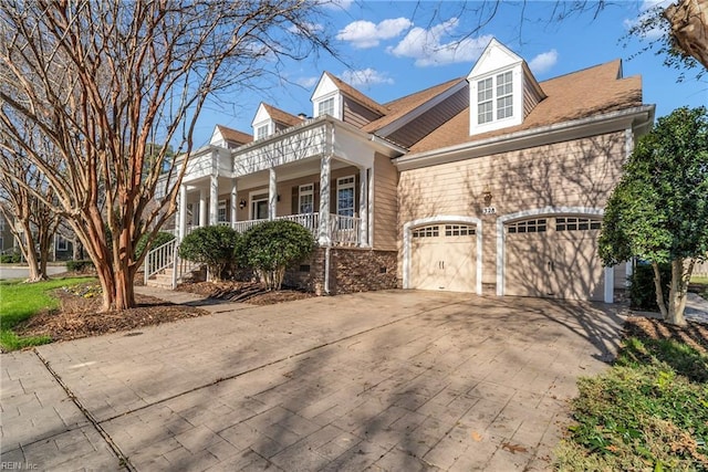 view of front facade with an attached garage, a balcony, driveway, and a porch