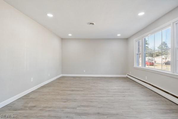 empty room with baseboard heating and light hardwood / wood-style floors