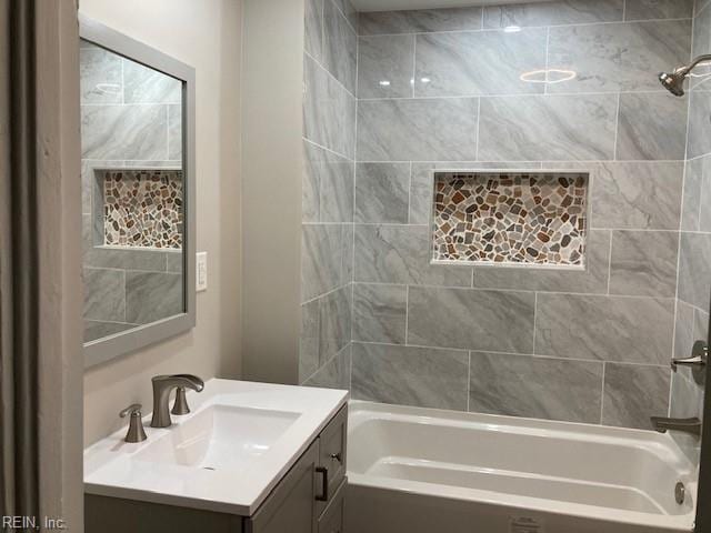 bathroom with tiled shower / bath and vanity